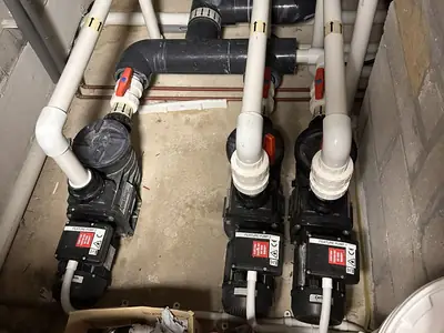 Three pool circulation pumps and their pipework in a plant room
