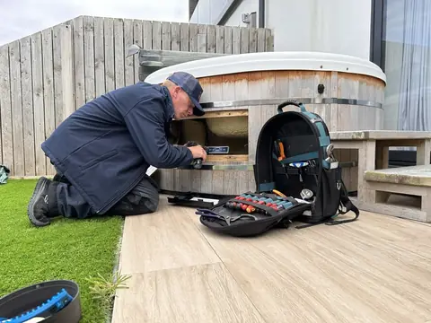 Engineer on site with his tool bag beside an open hot tub cabinet