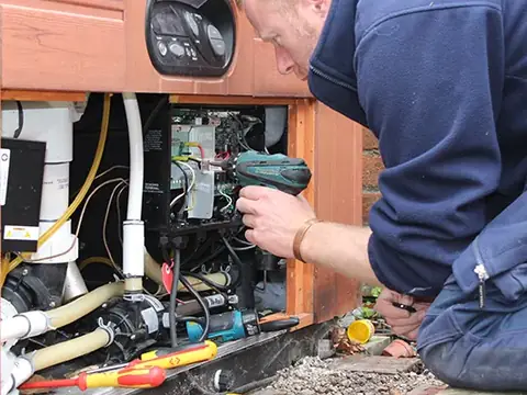 Jon Pennington using a cordless screwdriver on a hot tub control pack