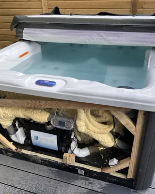 Hot tub with its side panel off, showing the foam insulation around the pipework and equipment
