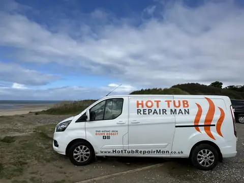 The Hot Tub Repair Man van parked on the grass above a sandy beach