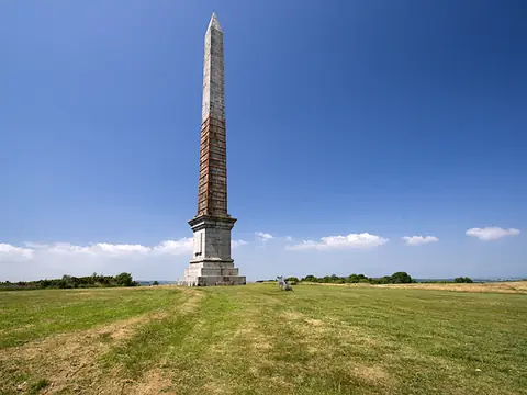 Gilbert’s Monument, a tall granite obelisk on Bodmin Beacon, against a cloudy sky