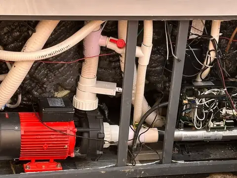 Inside a hot tub equipment bay: the red pump, heater, control pack and pipework