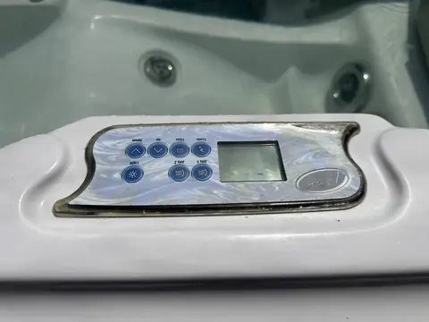 Hot tub topside control panel with its display and buttons, set into the edge of the tub