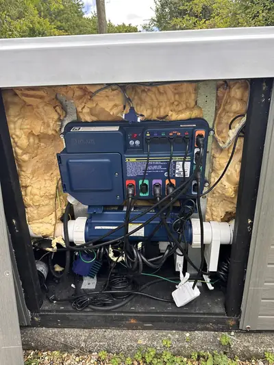 Open hot tub equipment bay showing the control pack, pump and wiring inside the foam insulation