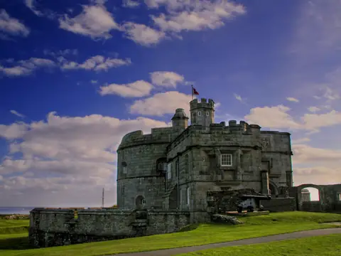 Pendennis Castle, a round stone keep inside low outer walls, on the grassy headland at Falmouth