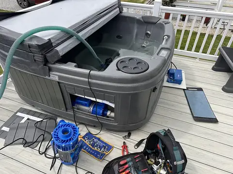 A grey RotoSpa hot tub on decking with its cover folded back, and parts and tools laid out beside it