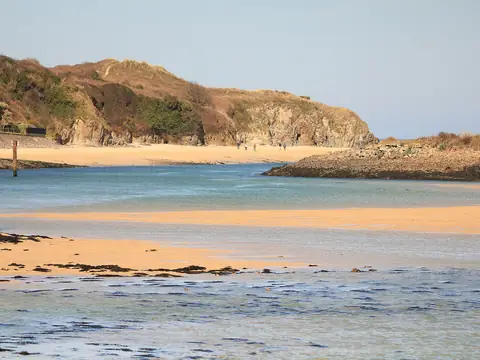 The Hayle estuary at low tide, with sandbanks, blue water and the cliffs at Lelant beyond