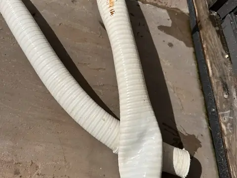 Flexible hot tub pipe with a split in it, lying on decking