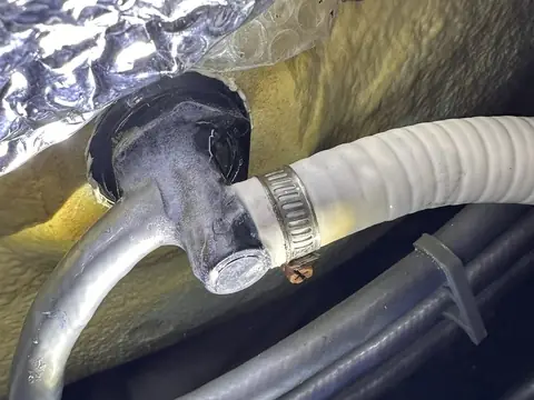 Pipe fitting exposed in cut-away foam insulation inside a hot tub cabinet