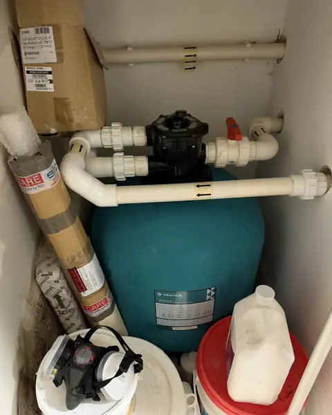 Sand filter with its multiport valve and pipework in a small pool plant room
