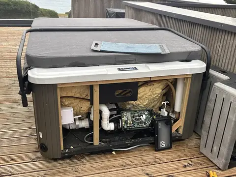 A Scarborough hot tub in Redruth with its side panels off and the pipework and equipment bay open