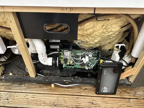 A new Balboa BP control system fitted in the equipment bay of an older hot tub, with pipework and foam insulation around it