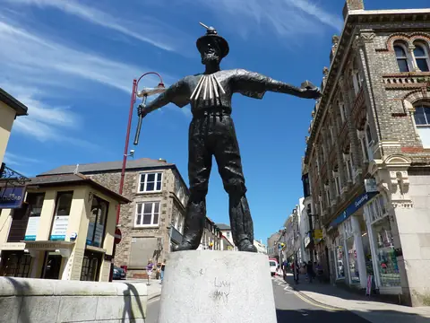 Bronze statue of a Cornish miner with arms outstretched, on a granite plinth in Redruth town centre