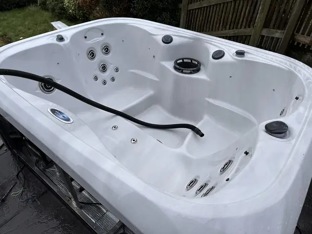 Clean, empty hot tub shell with a hose lying in it during a service
