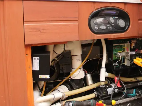 Hot tub cabinet opened up for a service, showing the pumps, pipework and control pack