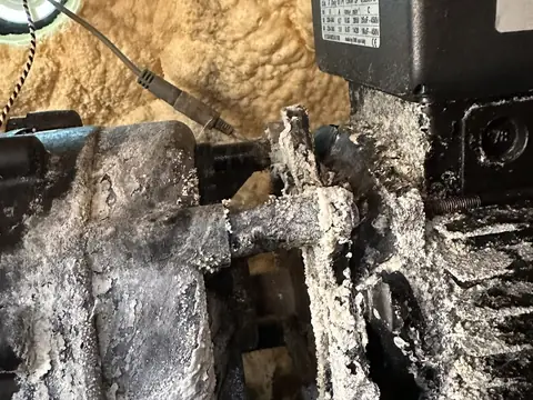 Hot tub pump motor covered in heavy white corrosion, inside a foam-filled cabinet
