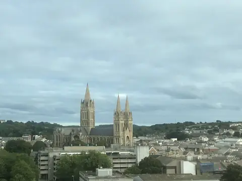 Distant view of the three spires of Truro Cathedral rising above the rooftops of Truro